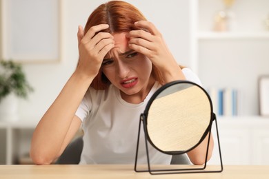 Photo of Suffering from allergy. Young woman with mirror checking her face at home