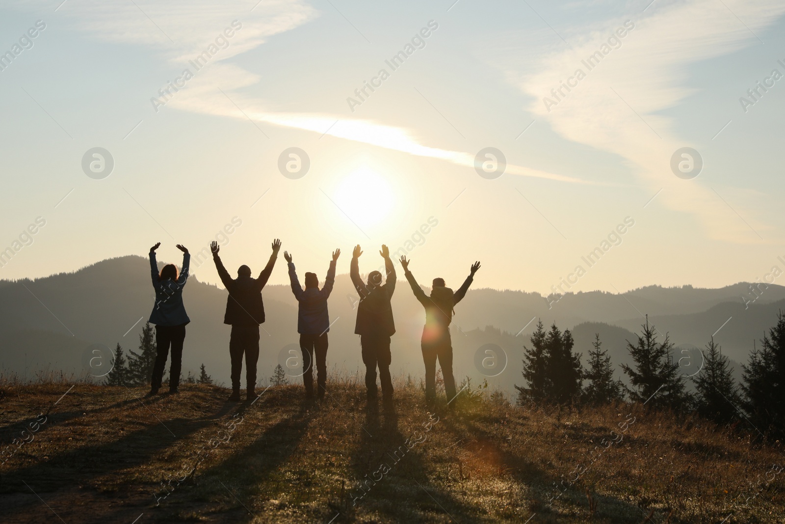 Photo of Group of people enjoying sunrise in mountains, back view