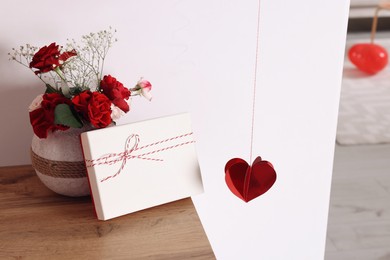 Vase with beautiful flowers and gift box on wooden table in room. Happy Valentine's Day