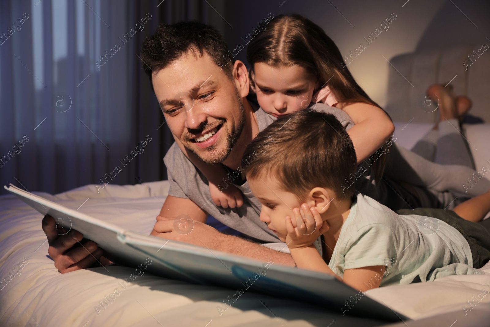 Photo of Father reading bedtime story to his children at home