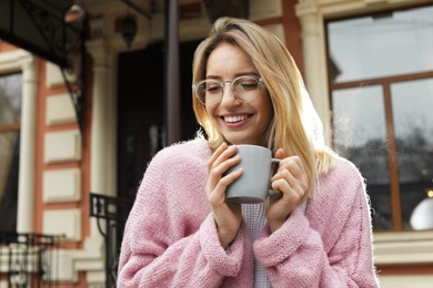 Photo of Young woman with cup of hot drink outdoors