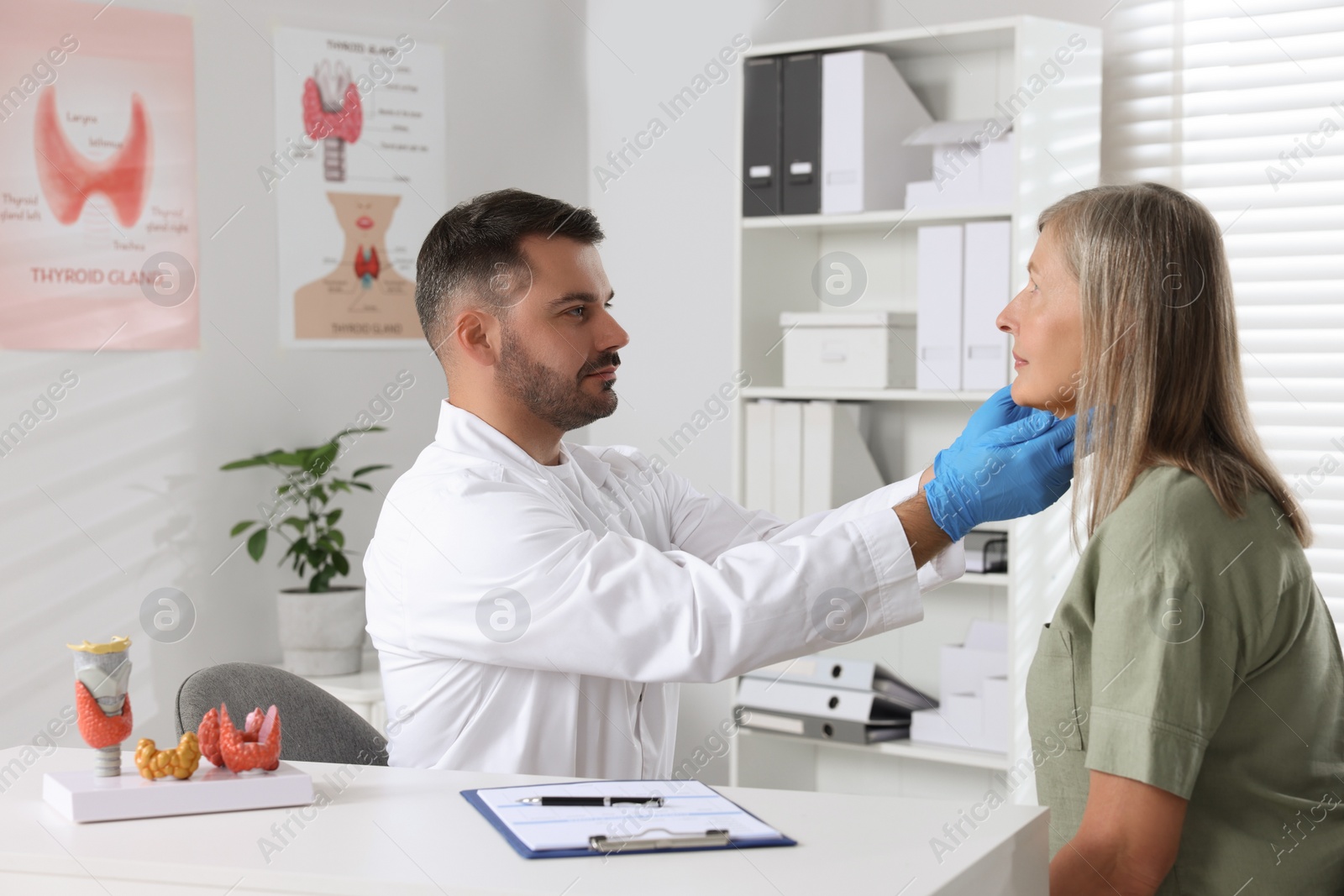 Photo of Endocrinologist examining thyroid gland of patient at table in hospital