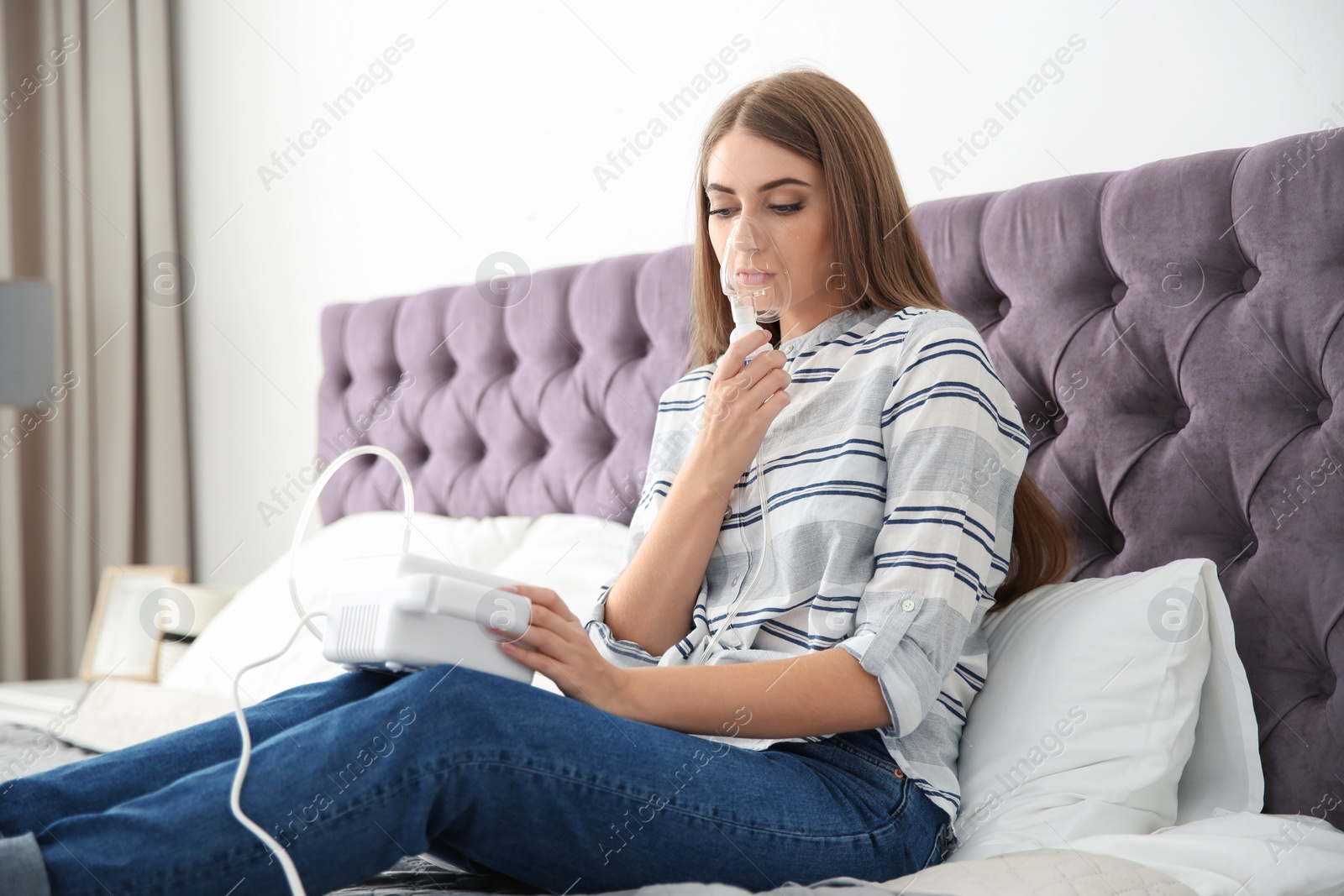 Photo of Young woman with asthma machine on bed in light room