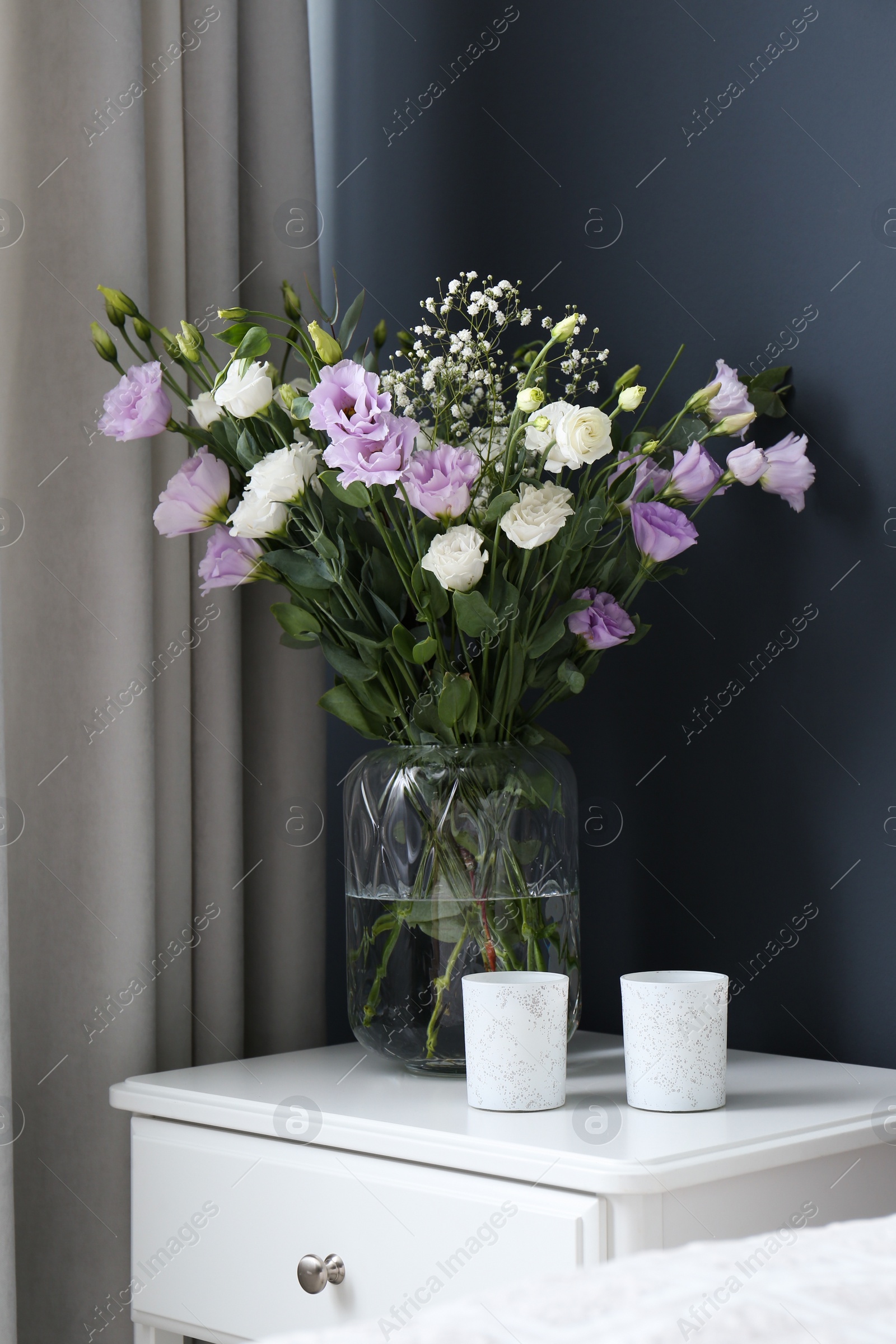 Photo of Bouquet of beautiful Eustoma flowers on nightstand in bedroom