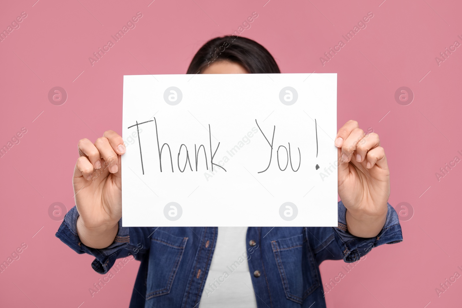 Photo of Woman holding card with phrase Thank You on pink background, selective focus