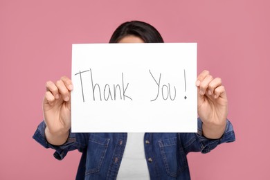 Woman holding card with phrase Thank You on pink background, selective focus