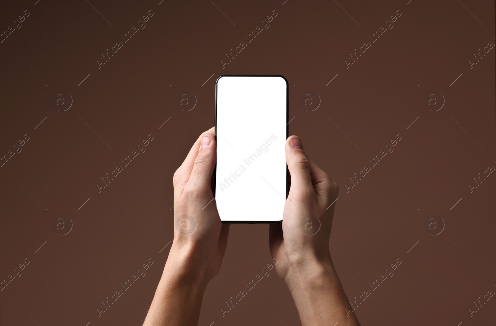 Photo of Man holding smartphone with blank screen on brown background, closeup. Mockup for design