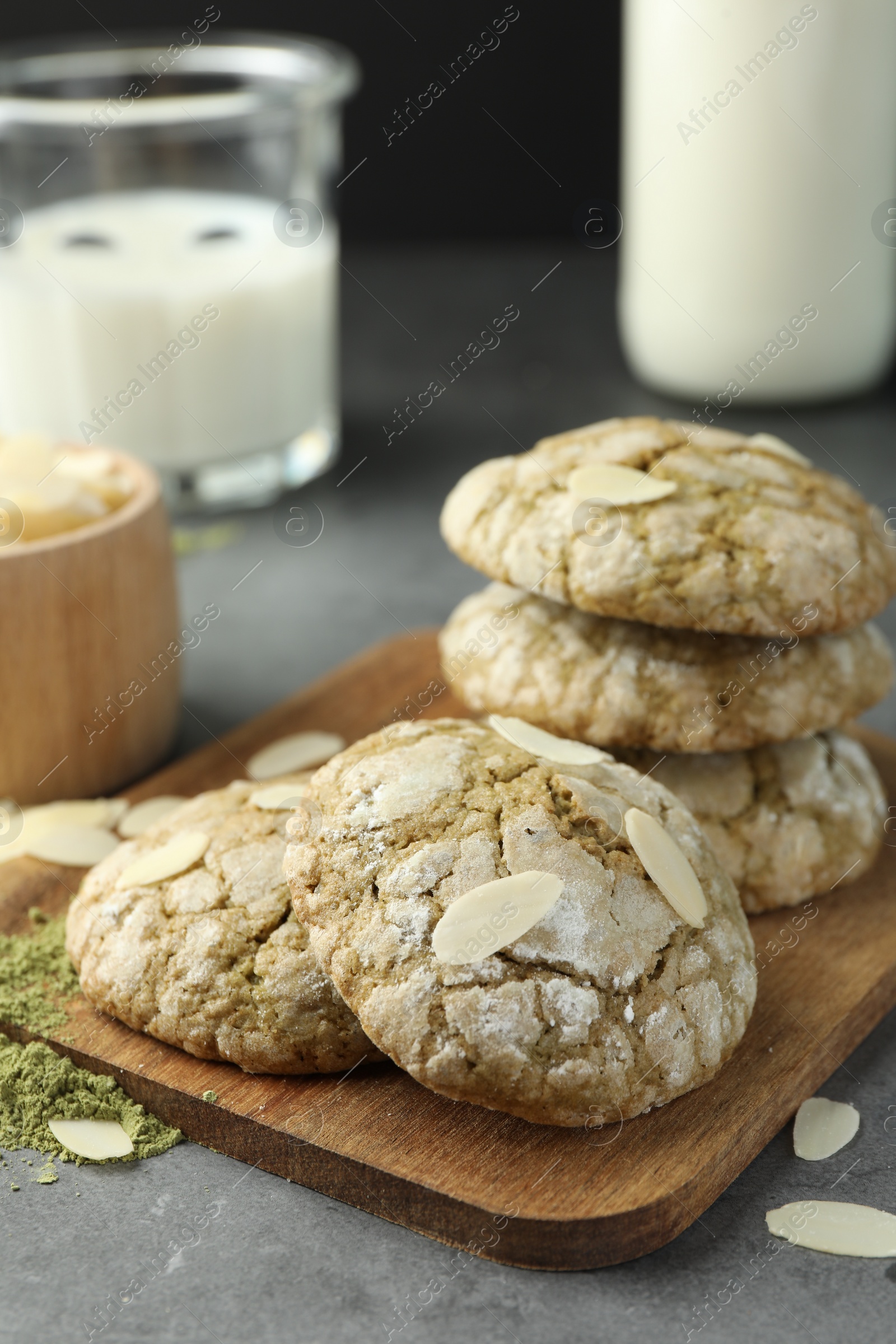 Photo of Tasty matcha cookies, almond flakes and powder on grey table