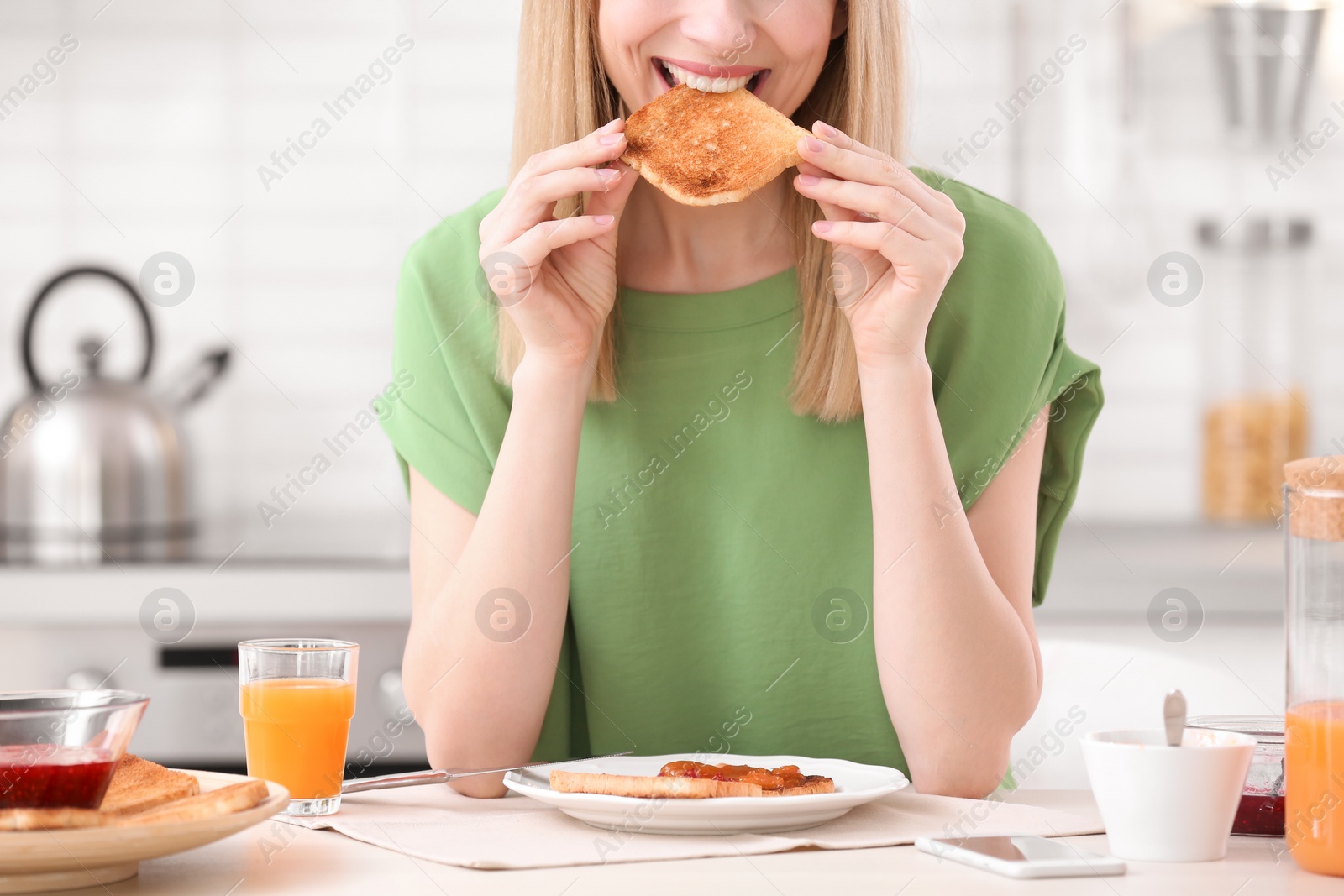 Photo of Beautiful woman eating tasty toasted bread with jam at table