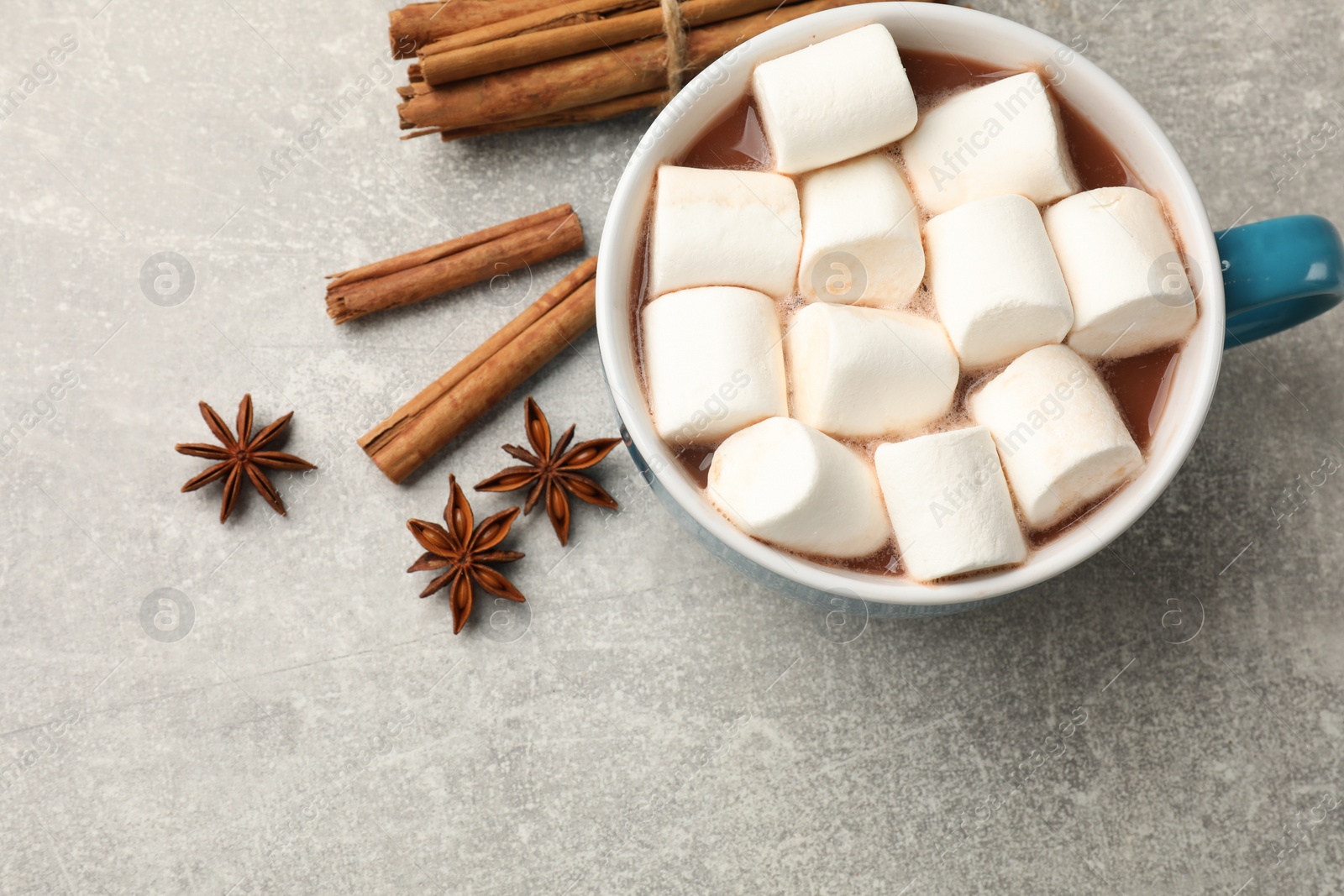 Photo of Tasty hot chocolate with marshmallows and spices on light grey table, flat lay