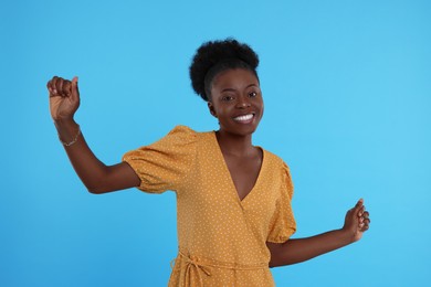 Photo of Beautiful young woman dancing on light blue background