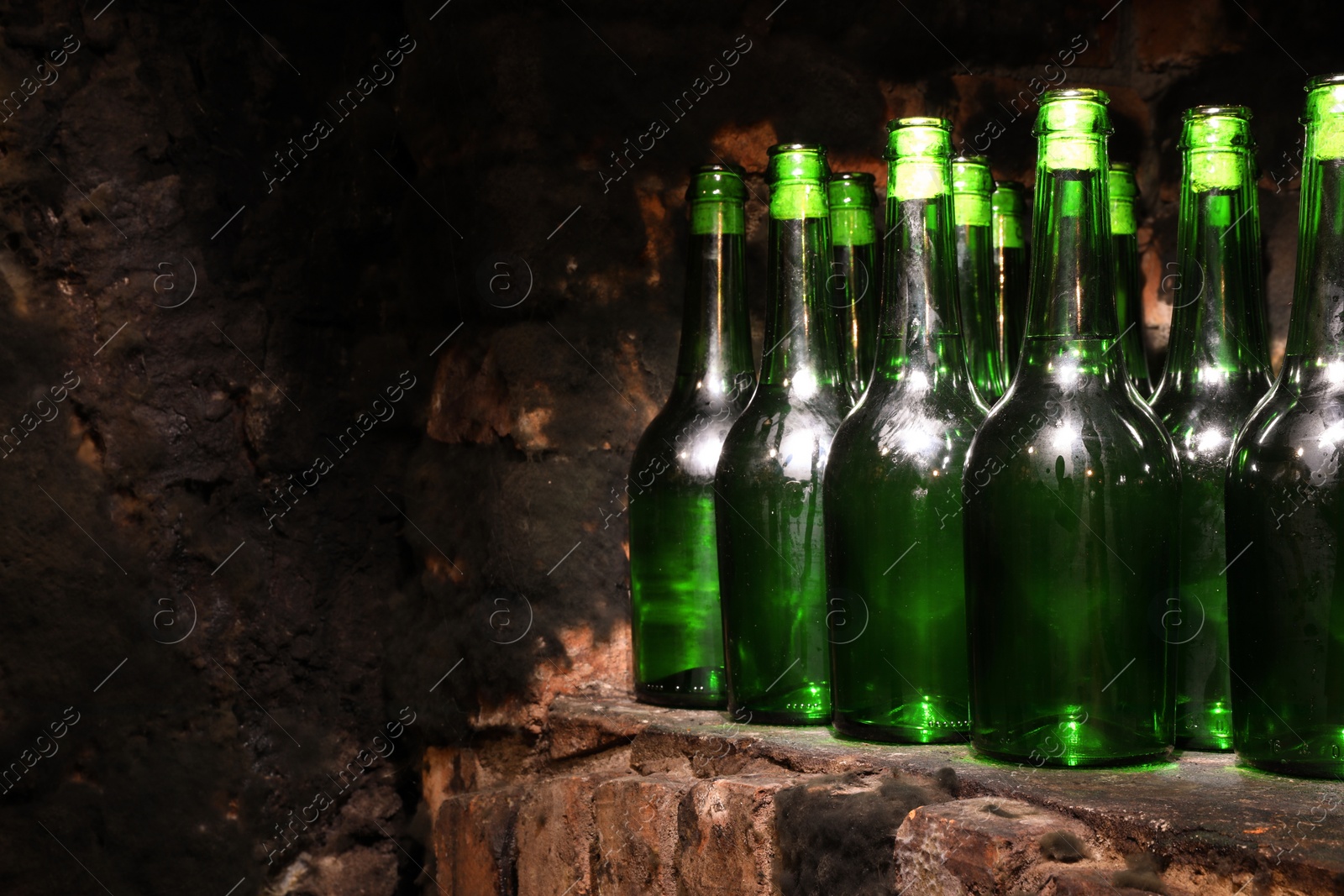 Photo of Many bottles of alcohol drinks on shelf in cellar, space for text