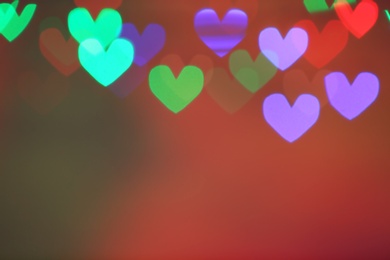 Photo of Blurred view of beautiful heart shaped lights on color background. Space for text