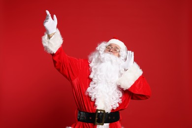 Photo of Merry Christmas. Santa Claus in headphones listening to music on red background