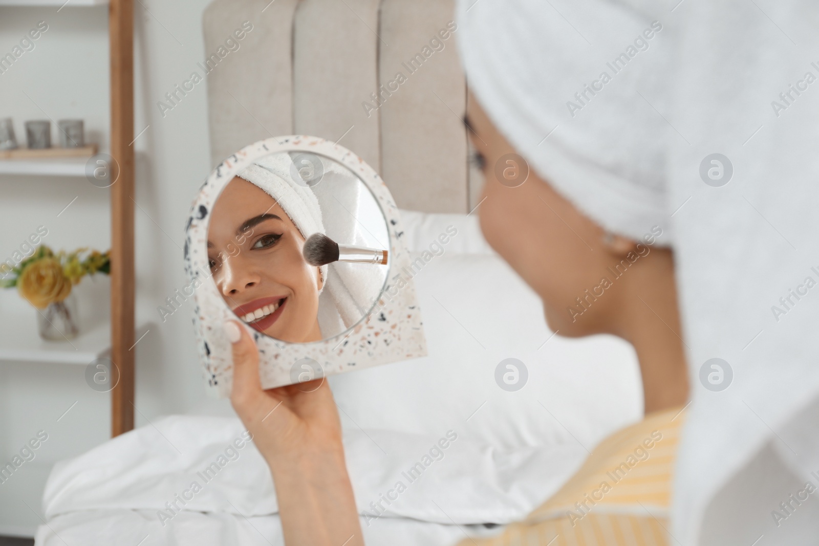 Photo of Beautiful woman with mirror applying makeup in bedroom, closeup