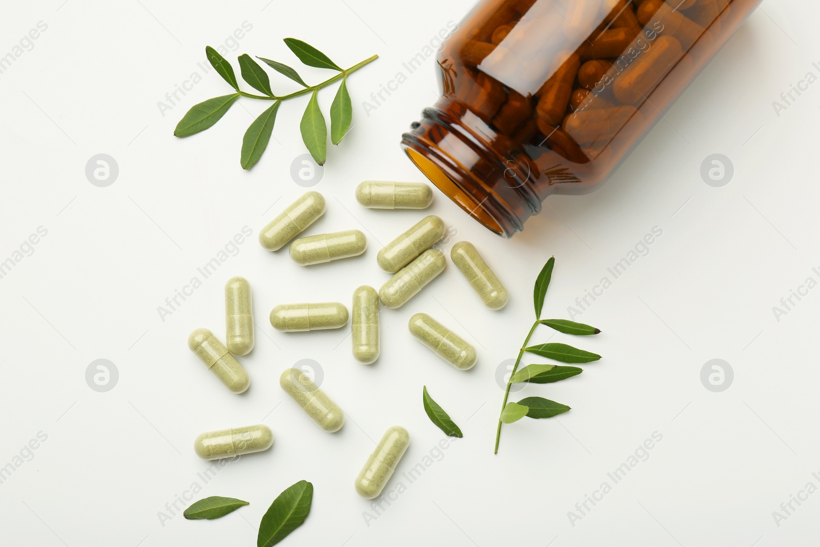 Photo of Bottle, vitamin capsules and leaves on white background, flat lay