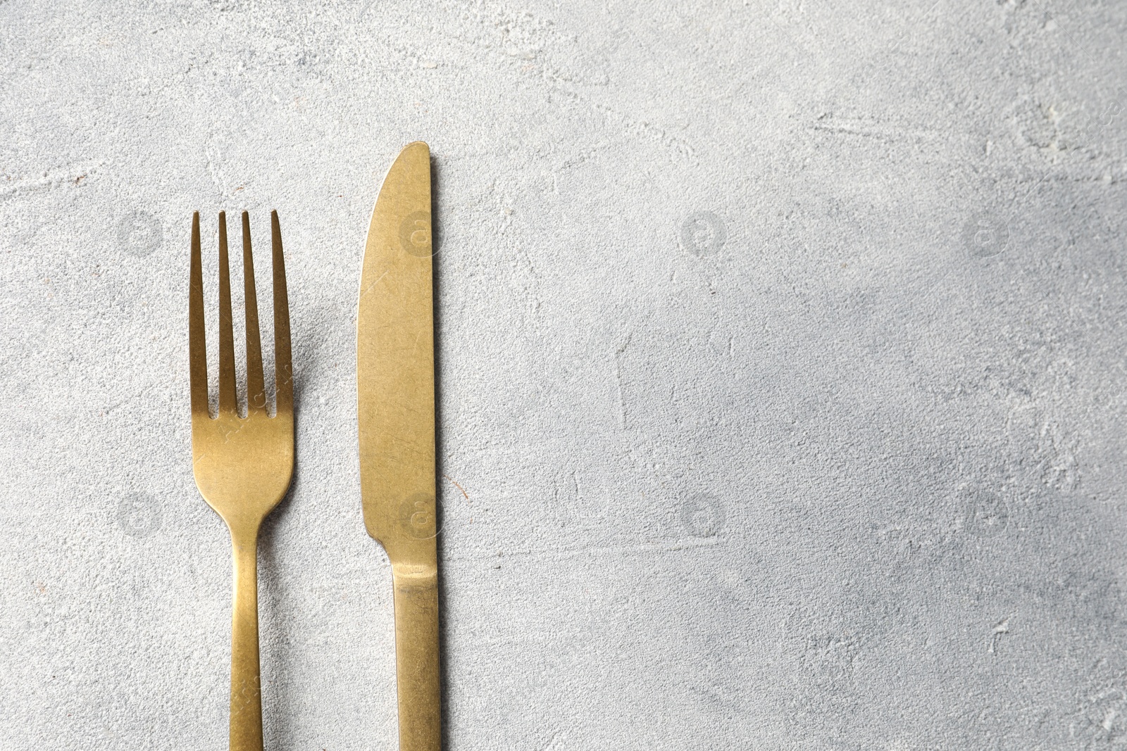 Photo of Stylish cutlery on light grey table, top view. Space for text