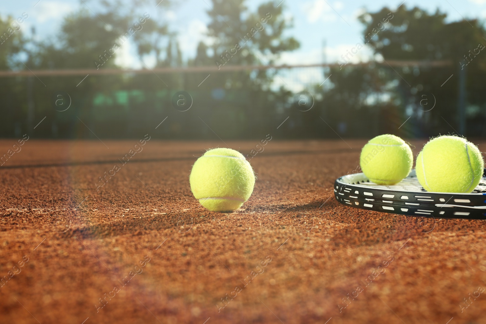 Photo of Tennis balls and racket on clay court