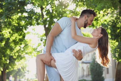 Lovely young couple dancing together in park on sunny day