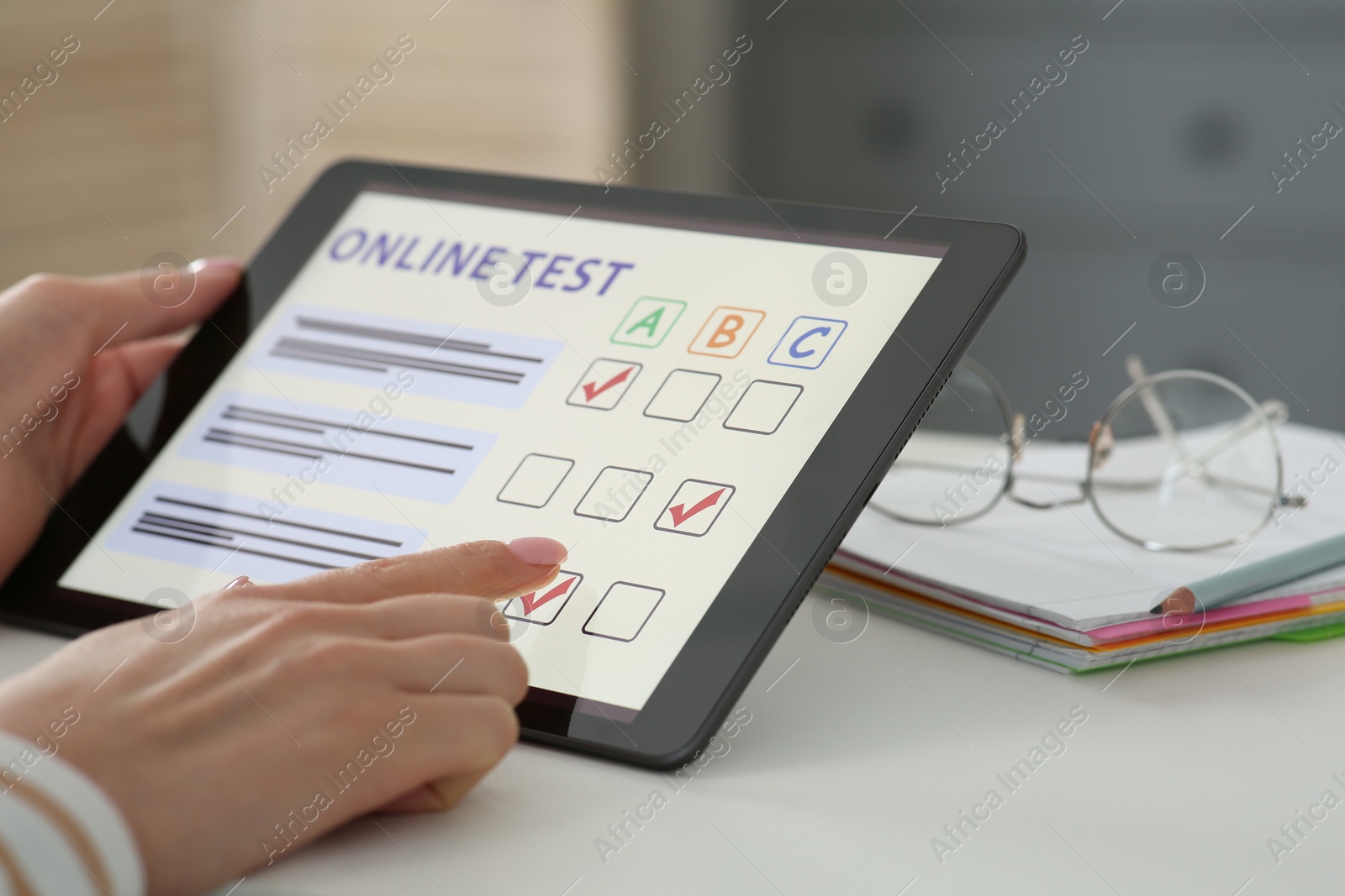 Photo of Woman taking online test on tablet at desk indoors, closeup