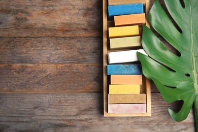 Photo of Many different handmade soap bars in wooden box, leaf and space for text on table, top view