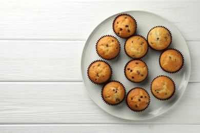 Photo of Delicious freshly baked muffins with chocolate chips on white wooden table, top view. Space for text