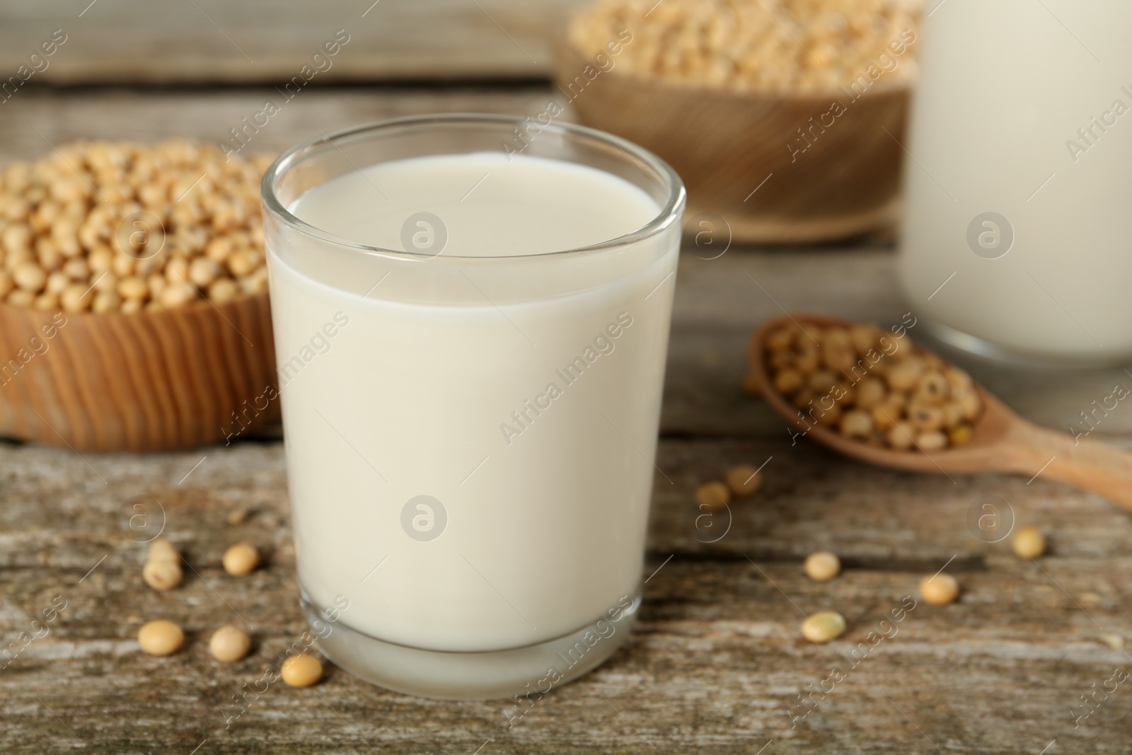 Photo of Glass with fresh soy milk and grains on wooden table, closeup