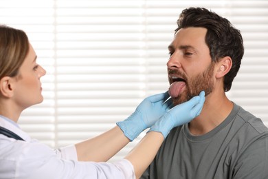 Photo of Doctor in medical gloves examining man`s oral cavity indoors