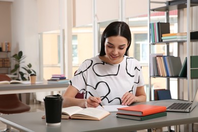 Young woman studying at table in library