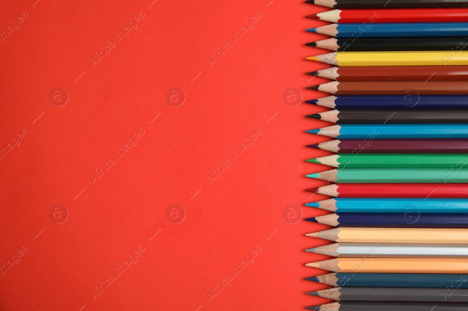 Photo of Flat lay composition with color pencils on red background. Space for text