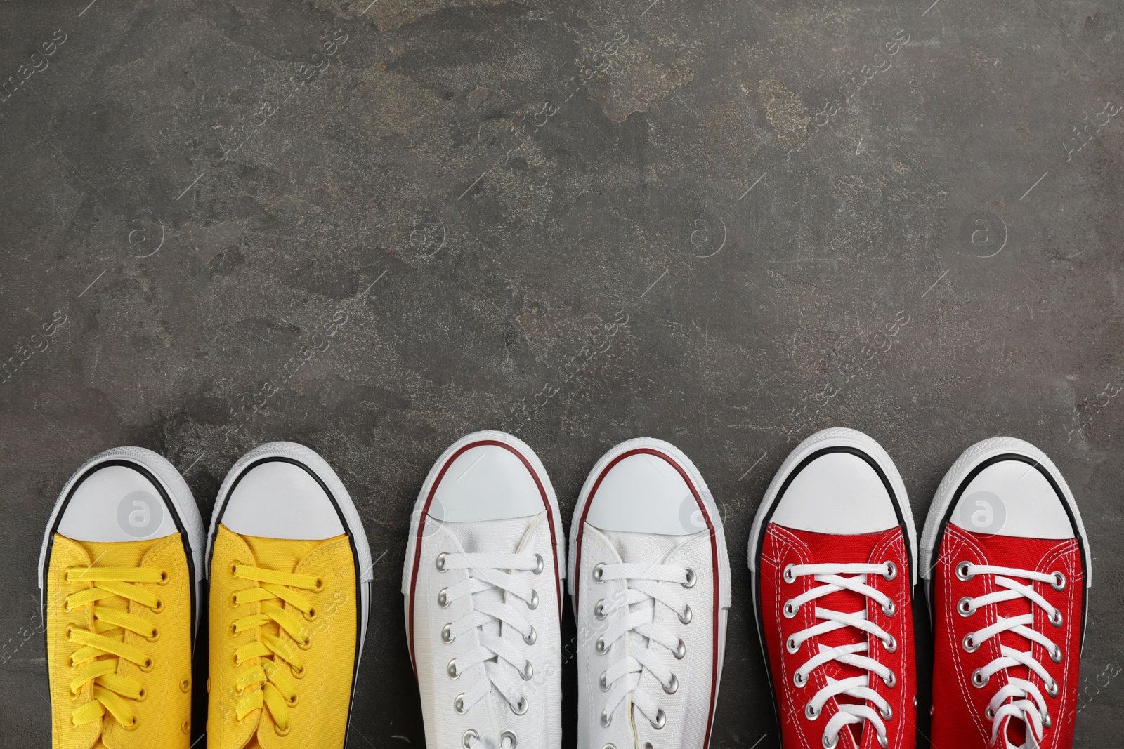 Photo of Different stylish sneakers on grey stone table, flat lay. Space for text