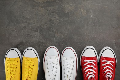 Photo of Different stylish sneakers on grey stone table, flat lay. Space for text