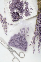 Scented sachet with dried lavender flowers and scissors on white wooden table, flat lay