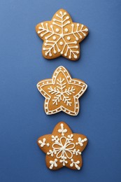 Photo of Tasty star shaped Christmas cookies with icing on blue background, flat lay