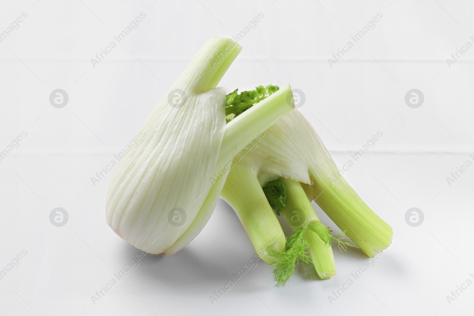 Photo of Fresh raw fennel bulbs on white table, closeup