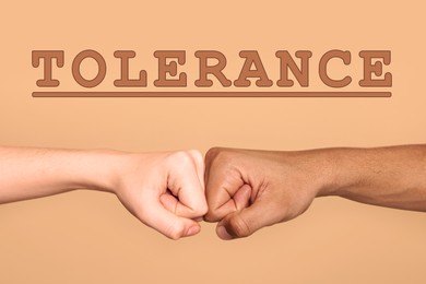 Tolerance, support and cooperation concept. People of different races making fist bump on light brown background, closeup