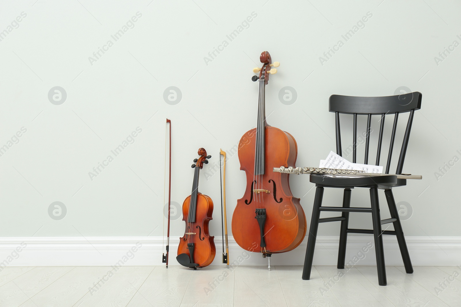 Photo of Stringed and wind musical instruments near white wall indoors, space for text