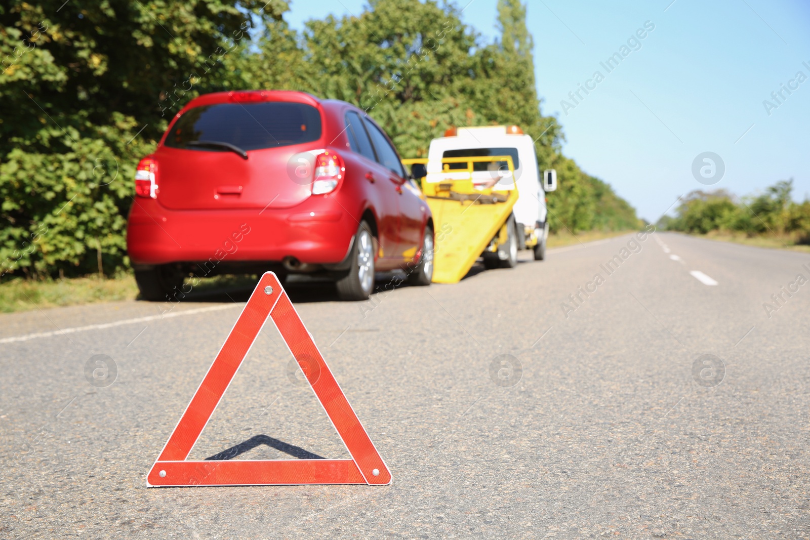 Photo of Emergency stop sign with broken car and tow truck on background. Space for text