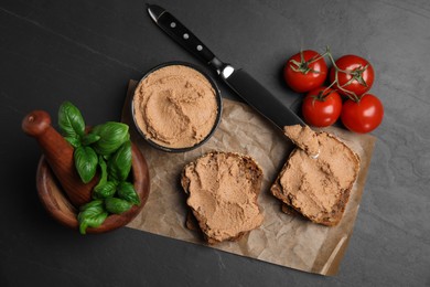 Photo of Fresh bread with delicious meat pate, cherry tomatoes and basil on black table, flat lay
