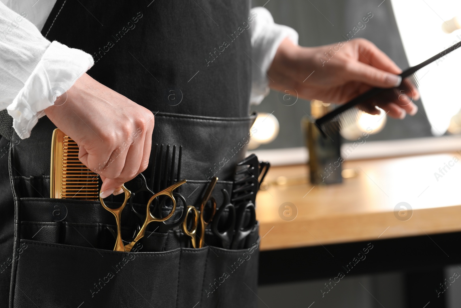 Photo of Hairstylist with professional tools in waist pouch in salon, closeup