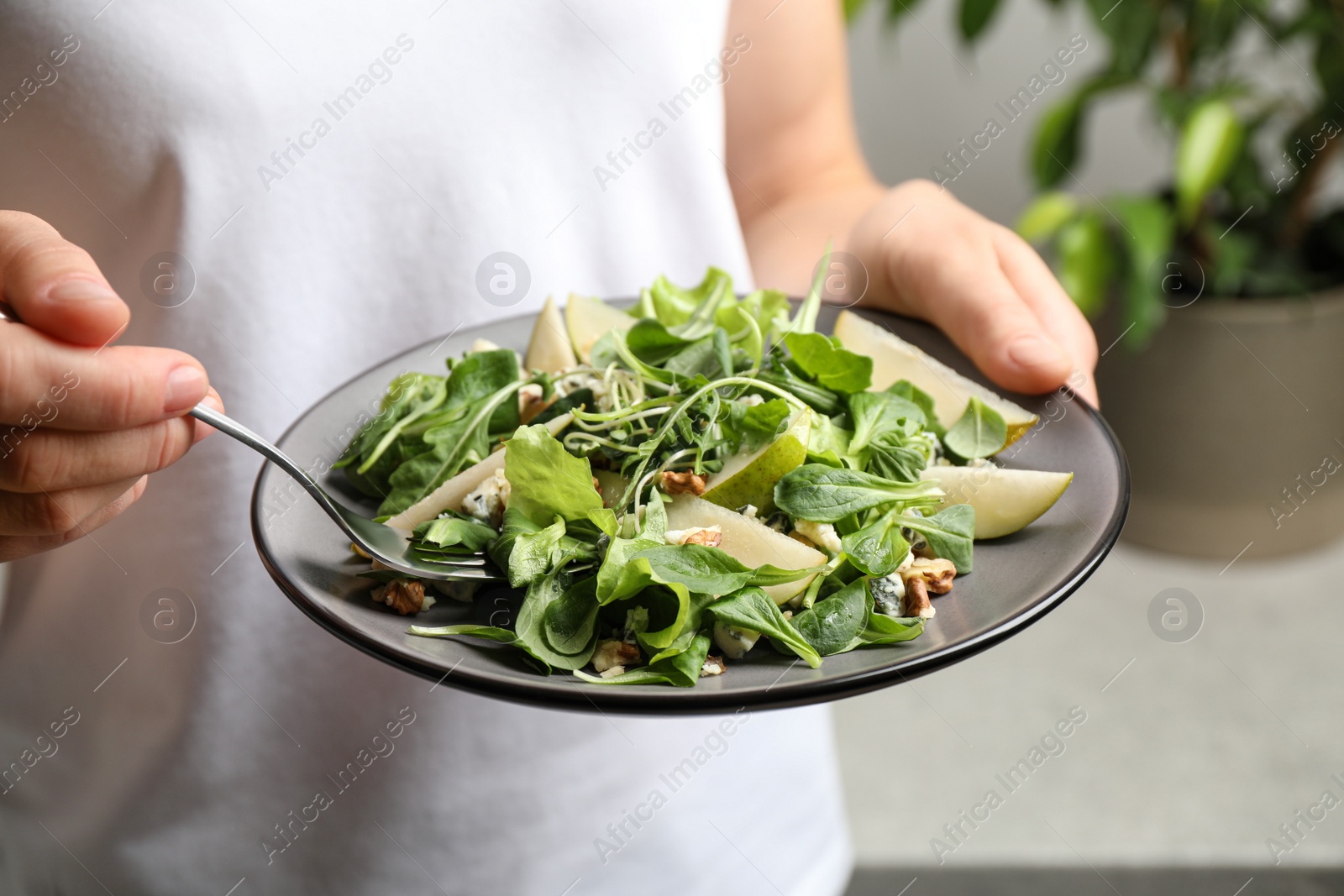 Photo of Woman with tasty pear salad on blurred background, closeup