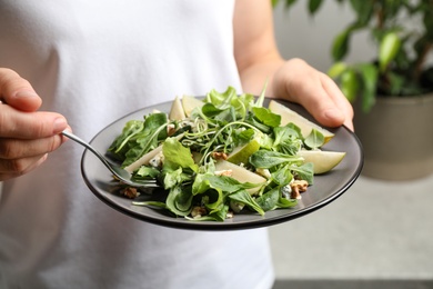 Photo of Woman with tasty pear salad on blurred background, closeup