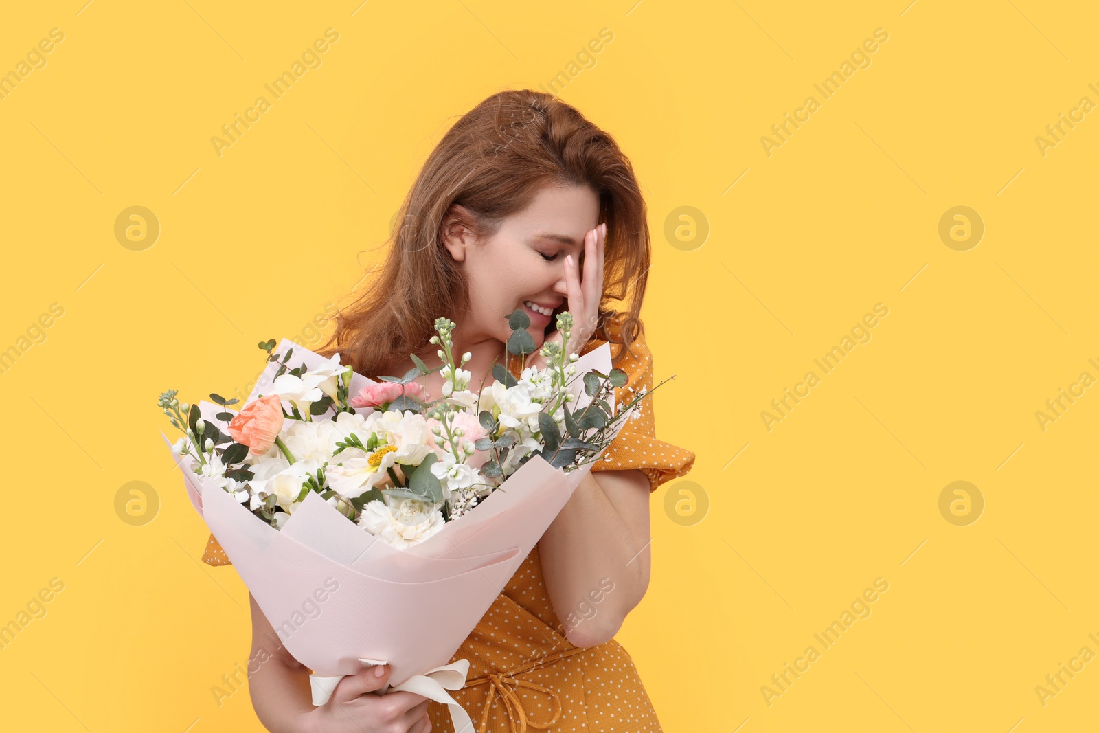 Photo of Happy woman with bouquet of beautiful flowers on yellow background