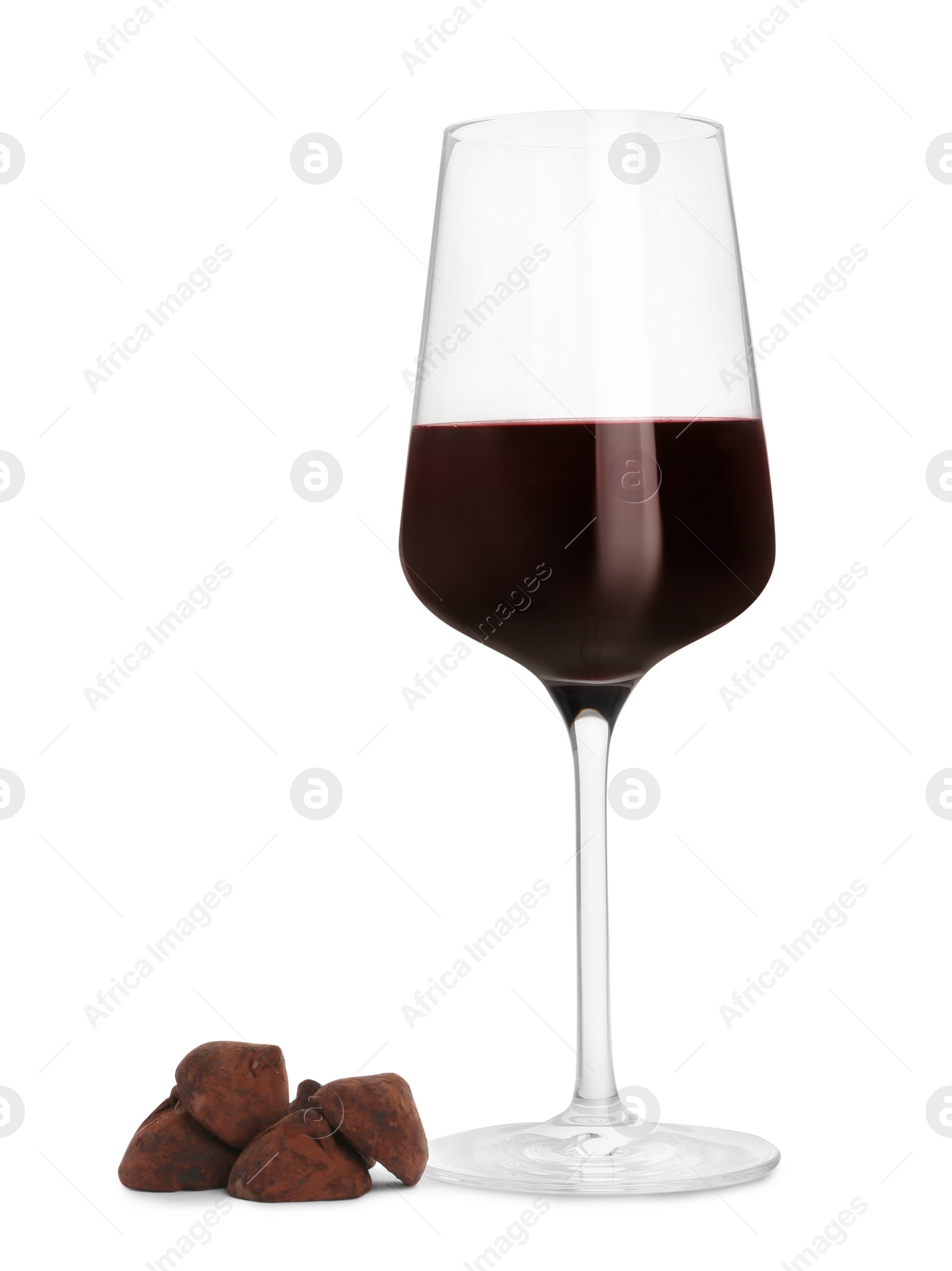 Photo of Glass of red wine and delicious chocolate candies on white background