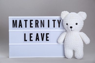 Photo of Lightbox with words Maternity Leave and toy bear on light grey background