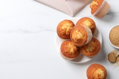 Delicious sweet muffins and brown sugar on white marble table, flat lay. Space for text