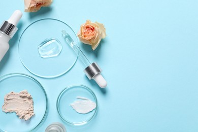 Bottle of cosmetic serum, flowers and petri dishes with samples on light blue background, flat lay. Space for text