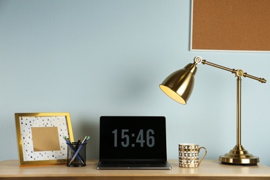 Modern workplace with laptop and golden decor on desk near wall. Stylish interior design