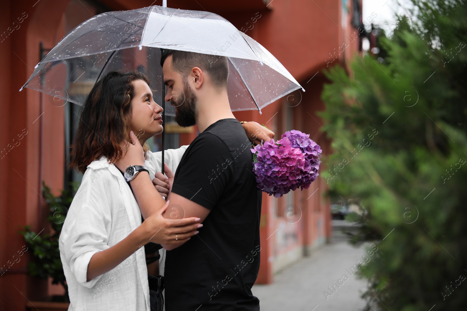 Photo of Young couple with umbrella enjoying time together under rain on city street, space for text