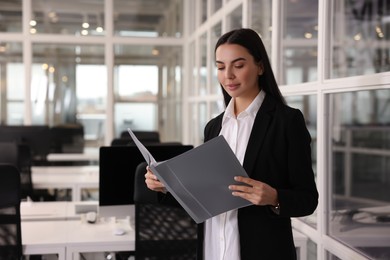 Beautiful woman with folder in office, space for text. Lawyer, businesswoman, accountant or manager